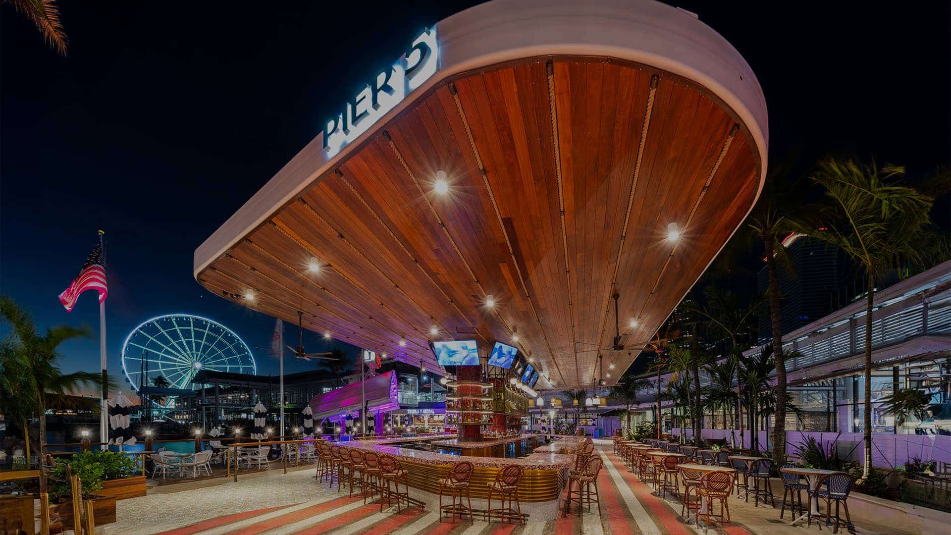 Evening harbor glow behind dining and gathering spaces at a Breakwater waterfront location.